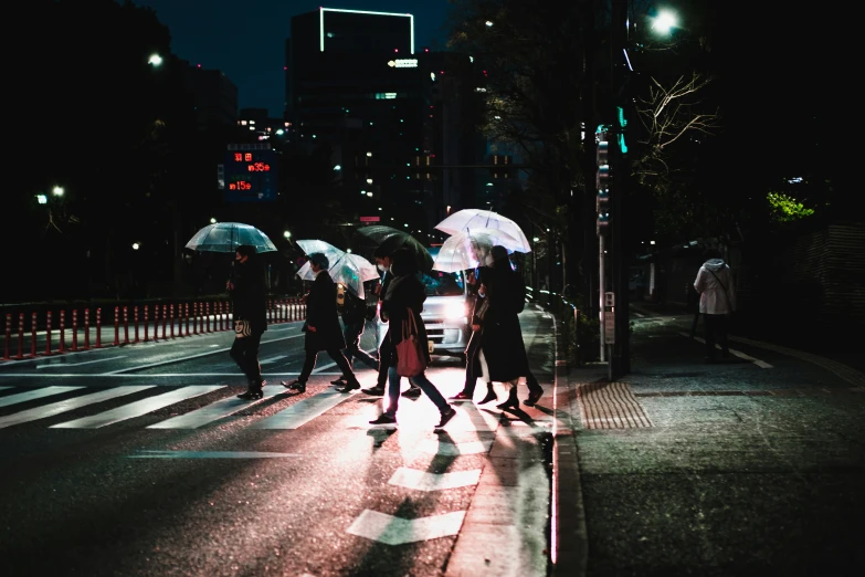 a group of people crossing a street in the rain