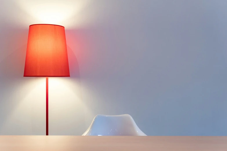 a modern red lamp next to an empty white chair