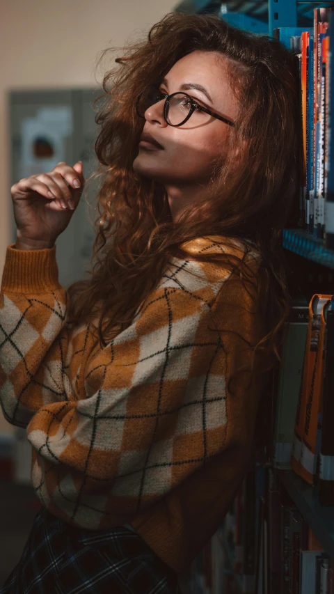 an attractive woman with glasses stands in front of some books