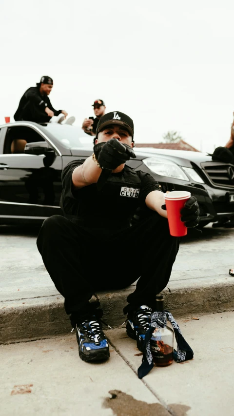 a man in black shirt holding a drink and crouching