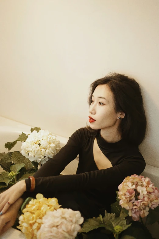 the woman is sitting on a bathtub near a bouquet of flowers