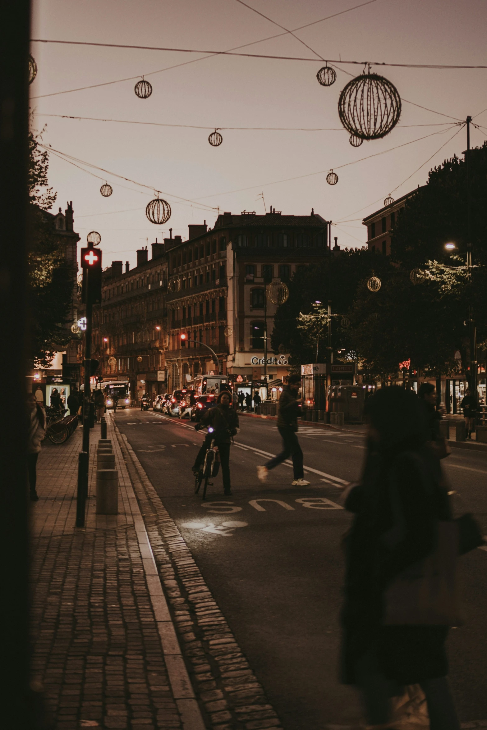 a city street with lights and people on bicycles