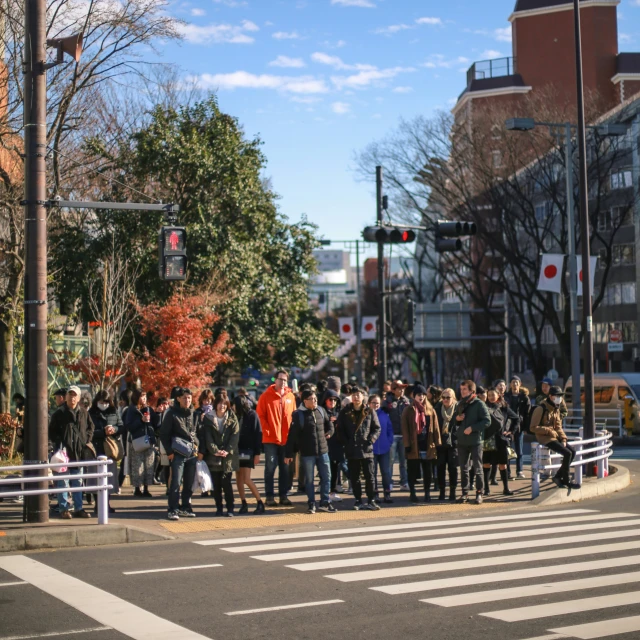 several people standing on the edge of a street next to a busy intersection