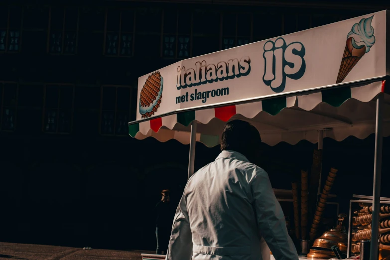 an old man standing under a street vendor that sells ice cream