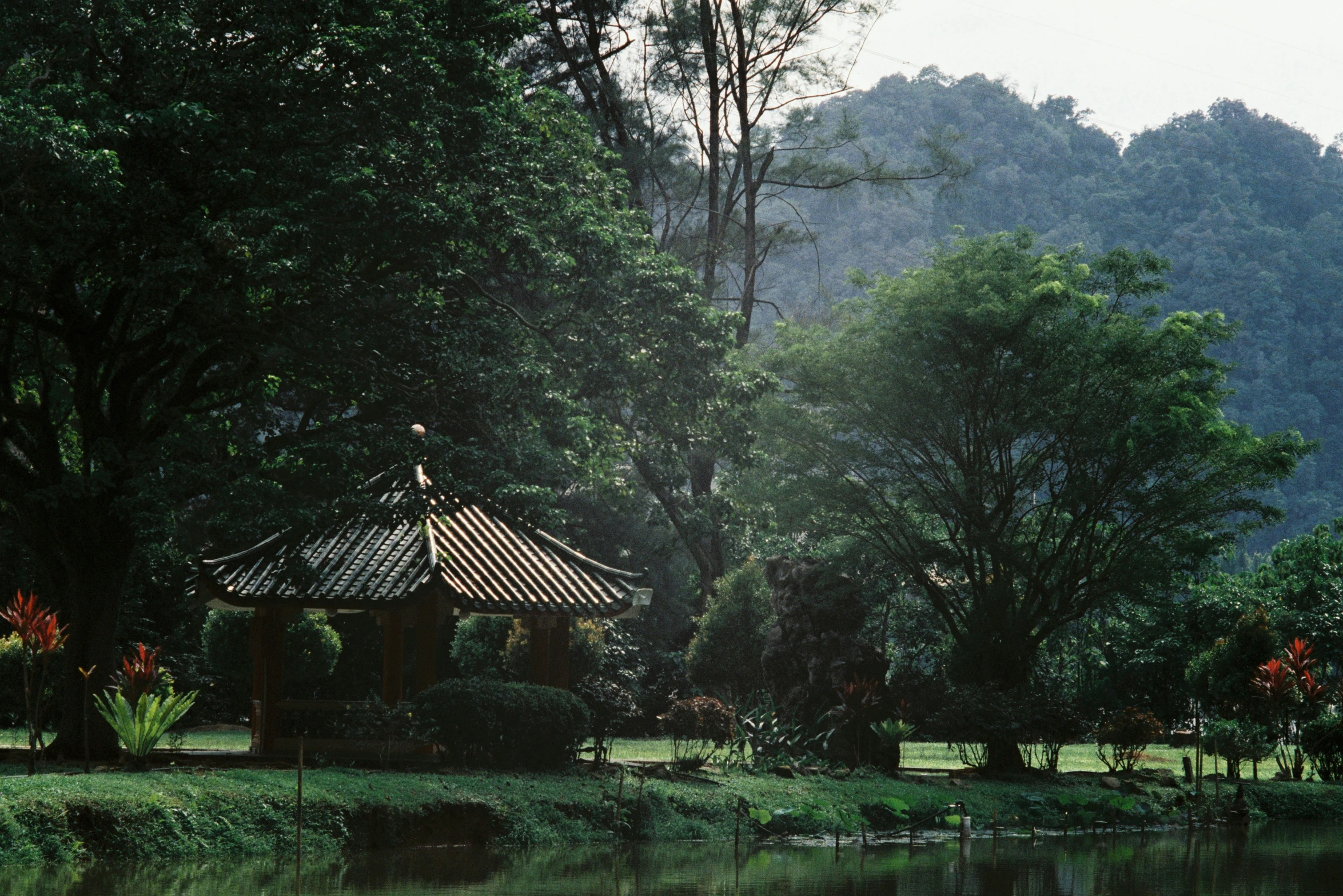 the gazebo is in the middle of the park next to the water