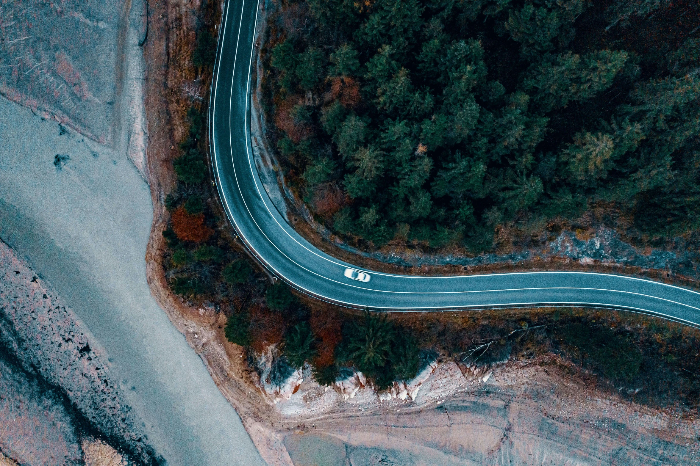 aerial view of highway with cars on road surrounded by forest