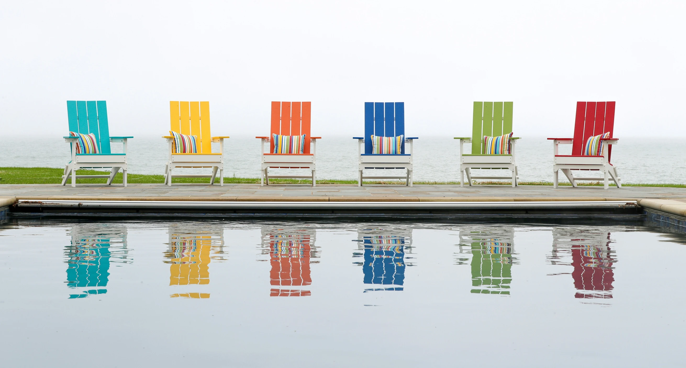 five lawn chairs sitting next to a small pier with reflections in the water