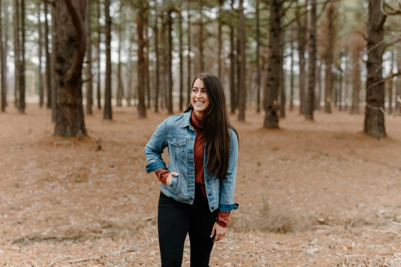 woman in blue jacket standing in a wooded area