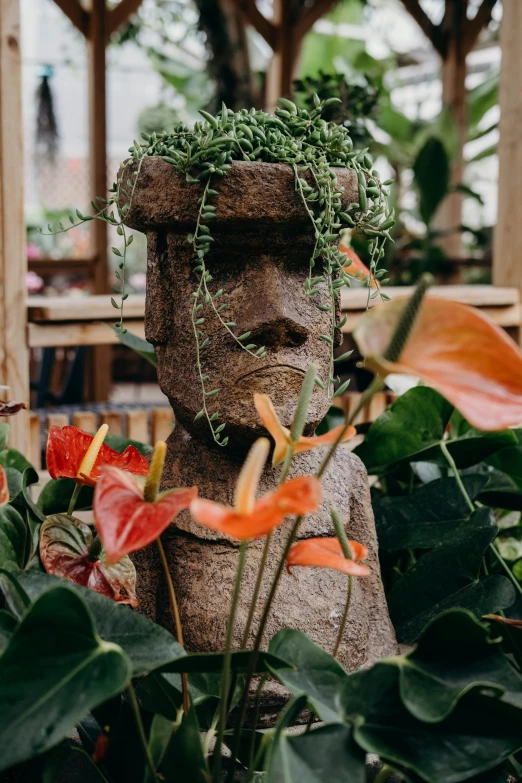 a plant is growing on a large statue in the middle of a garden