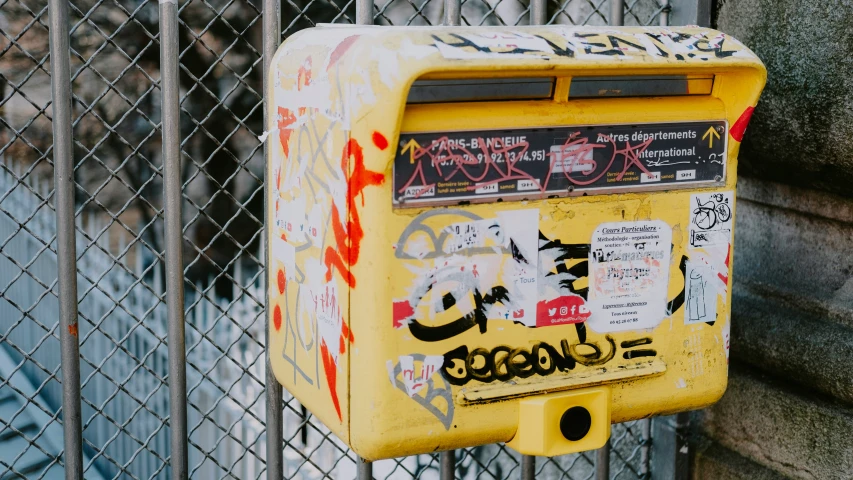 the post box is surrounded by graffiti on the fence