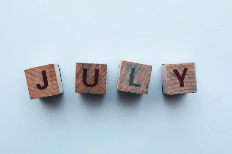 blocks spell out the word july on a blue background