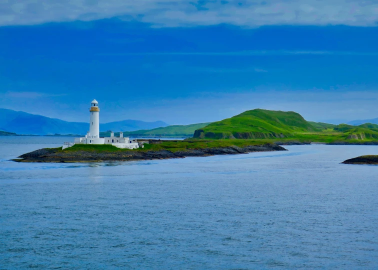 a lighthouse surrounded by water in the middle of some mountains