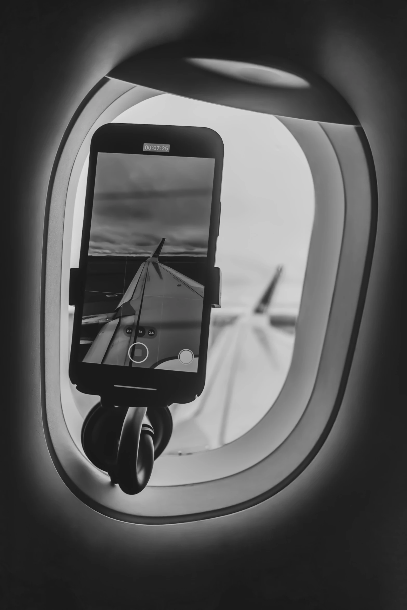 an airplane window view, with the seat and handle extended, is showing a black - and - white po