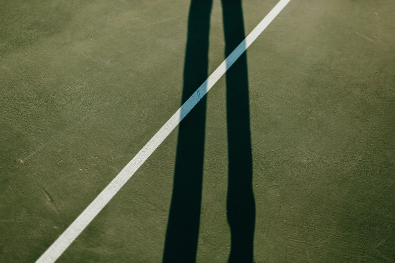 shadow of tennis player over court with ball and racket