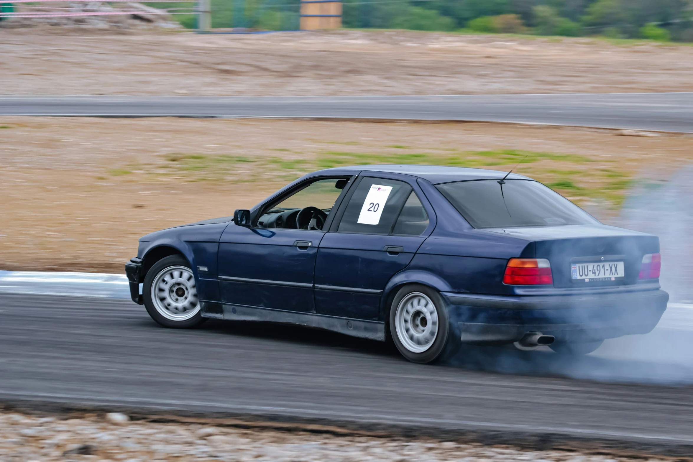 an automobile driving on a track with smoke