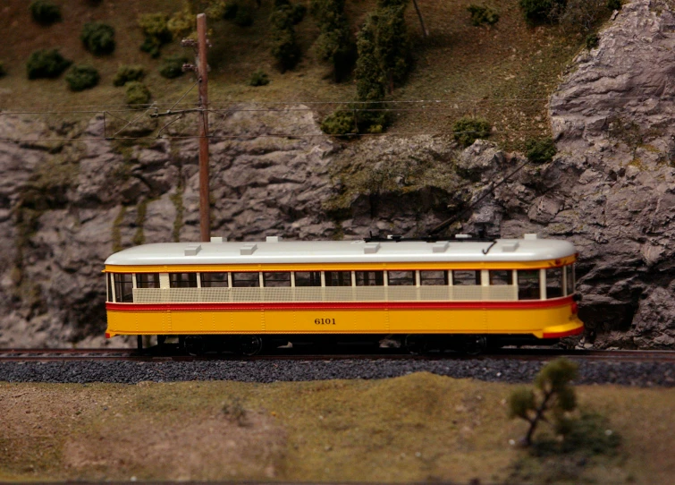 a yellow, red and white train car traveling down railroad tracks