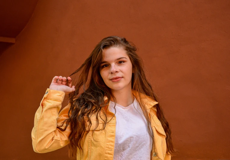 girl in a yellow jacket and white shirt holds her hands up