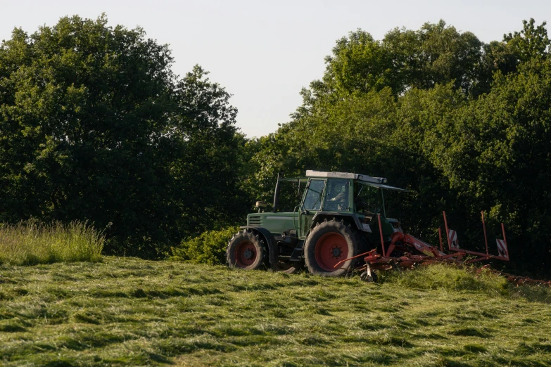 an old tractor parked on a field near some trees