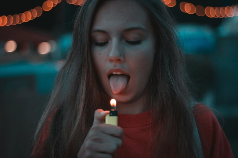 a woman holds her tongue open to light a lighter