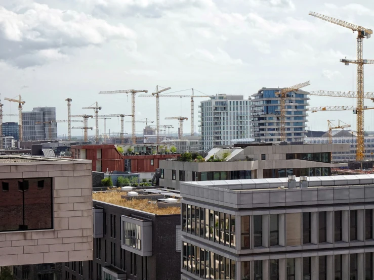 a few buildings with lots of tall construction cranes behind them