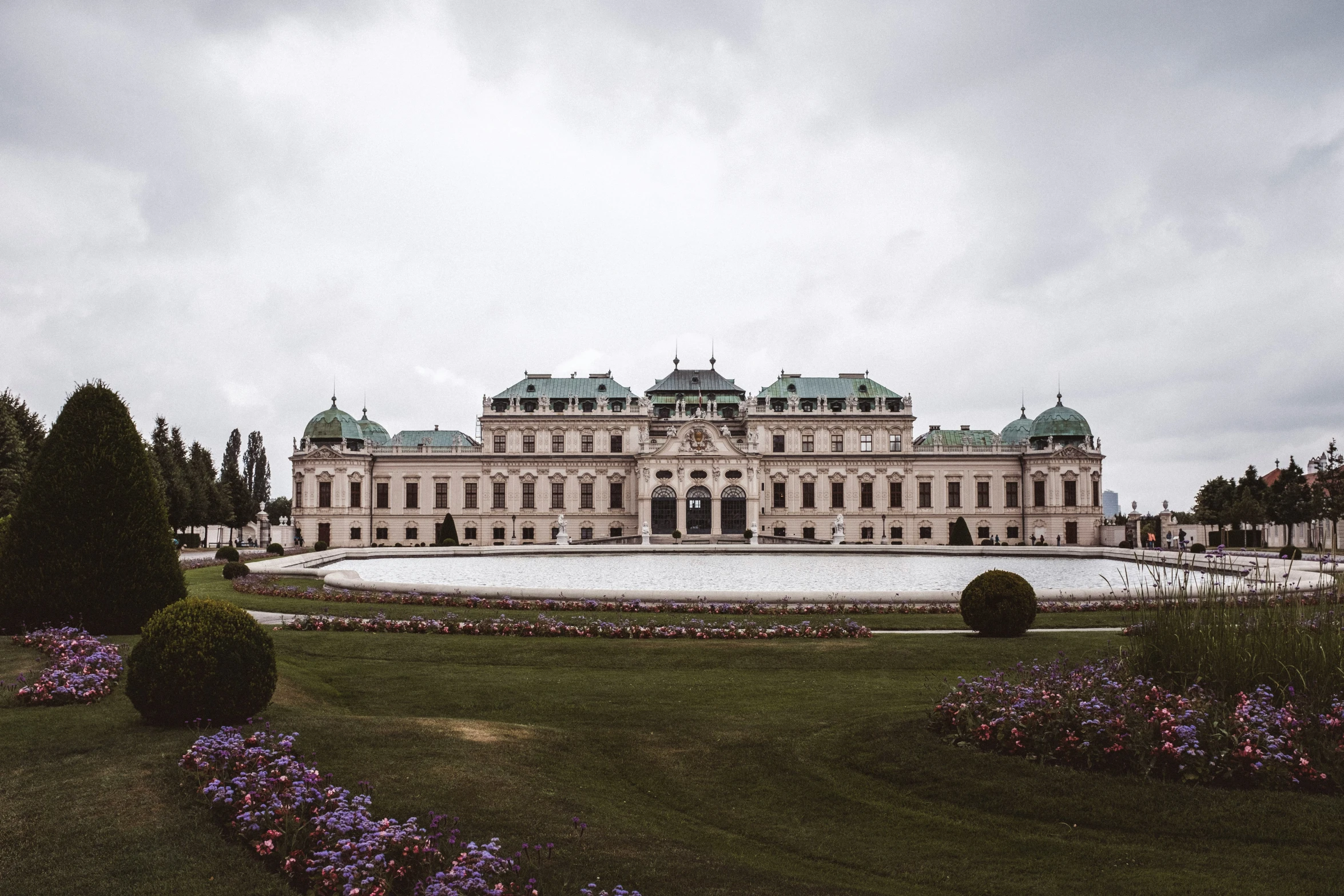 an outdoor area of a mansion, which has lots of flowers in the middle