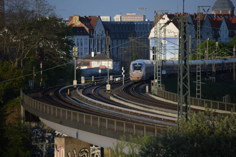 two silver trains traveling down the train tracks