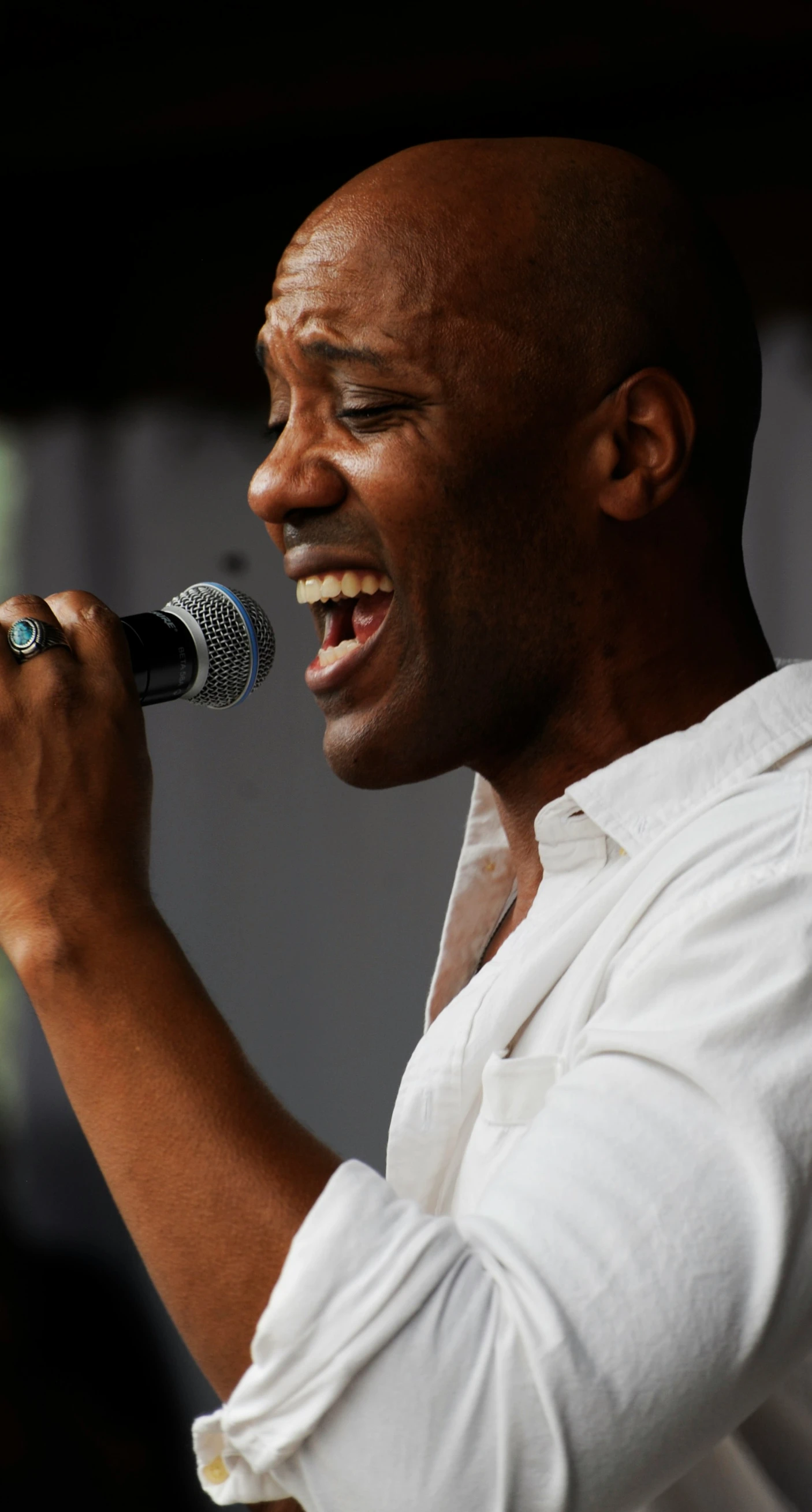 the man smiles while singing into the microphone