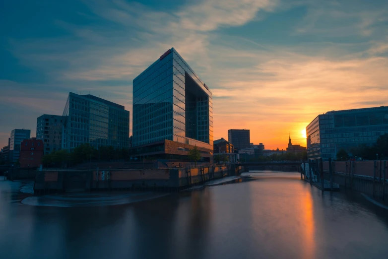 sunset near the water as it reflects the building on the other side of the waterway