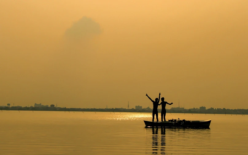 two people standing on a boat in a body of water