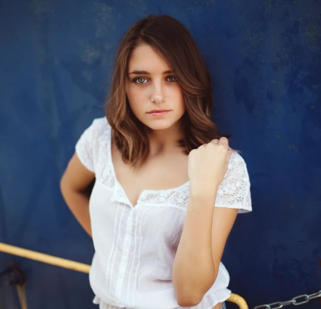 a young woman poses by some blue wall