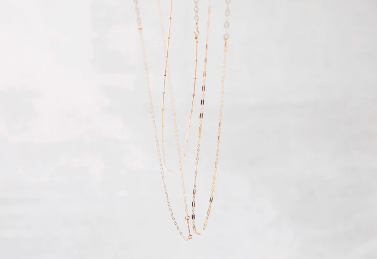 gold colored necklaces with beads hanging from chains