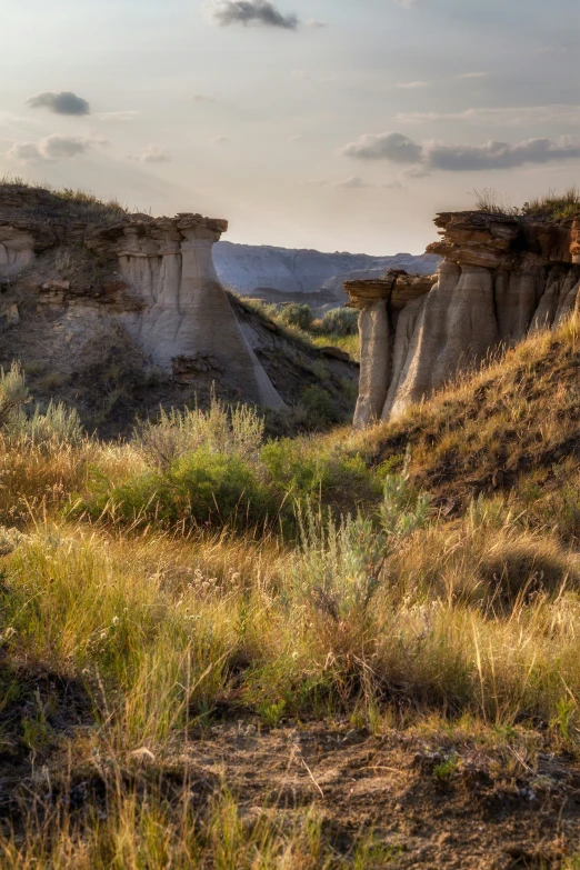 a small group of cliffs sitting above grass and dirt