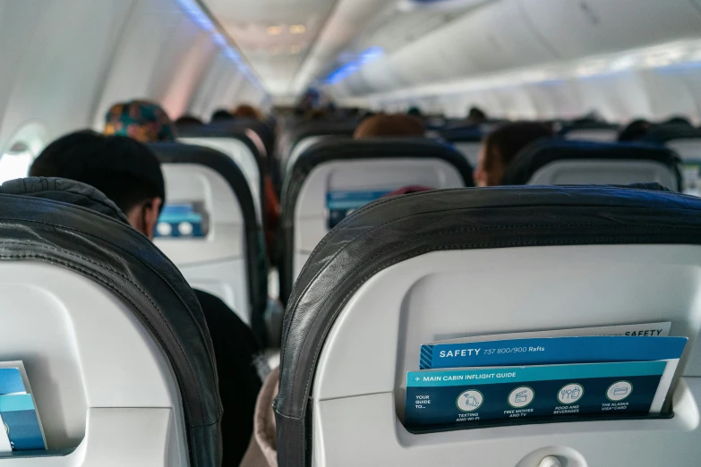 a person sitting on an airplane seat and writing on the computer