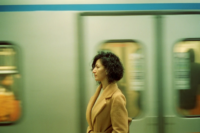 an woman in a beige coat walking past train