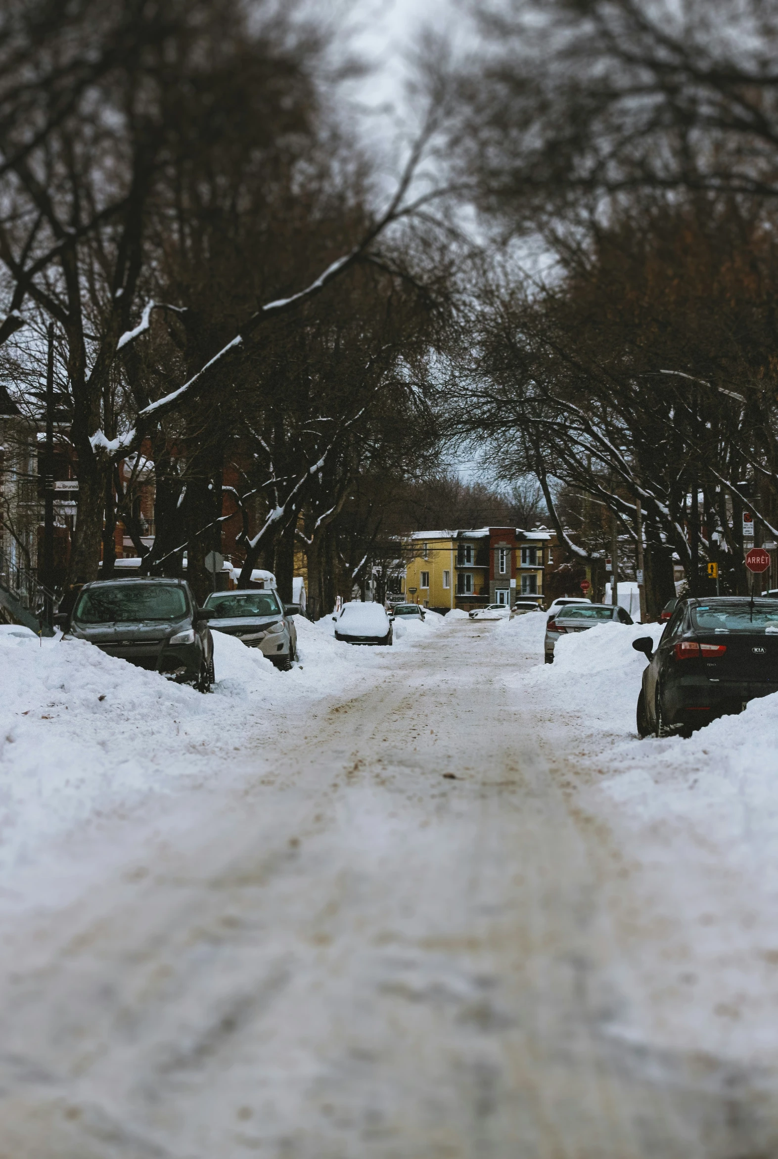 a snowy street with a car parked on the side of it