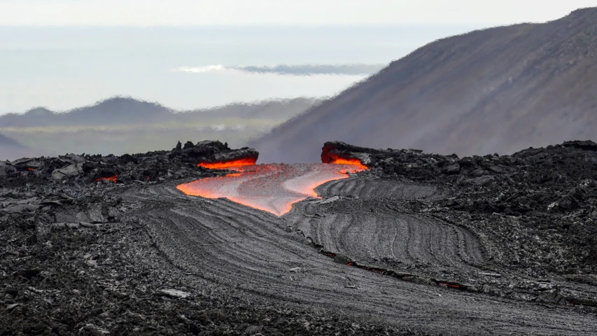 lava coming out from a volcano in the middle of mountains