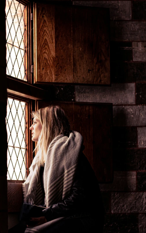 woman sitting on ledge with open window looking at outdoors