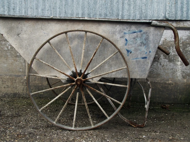 a old looking wheel sitting next to a wall