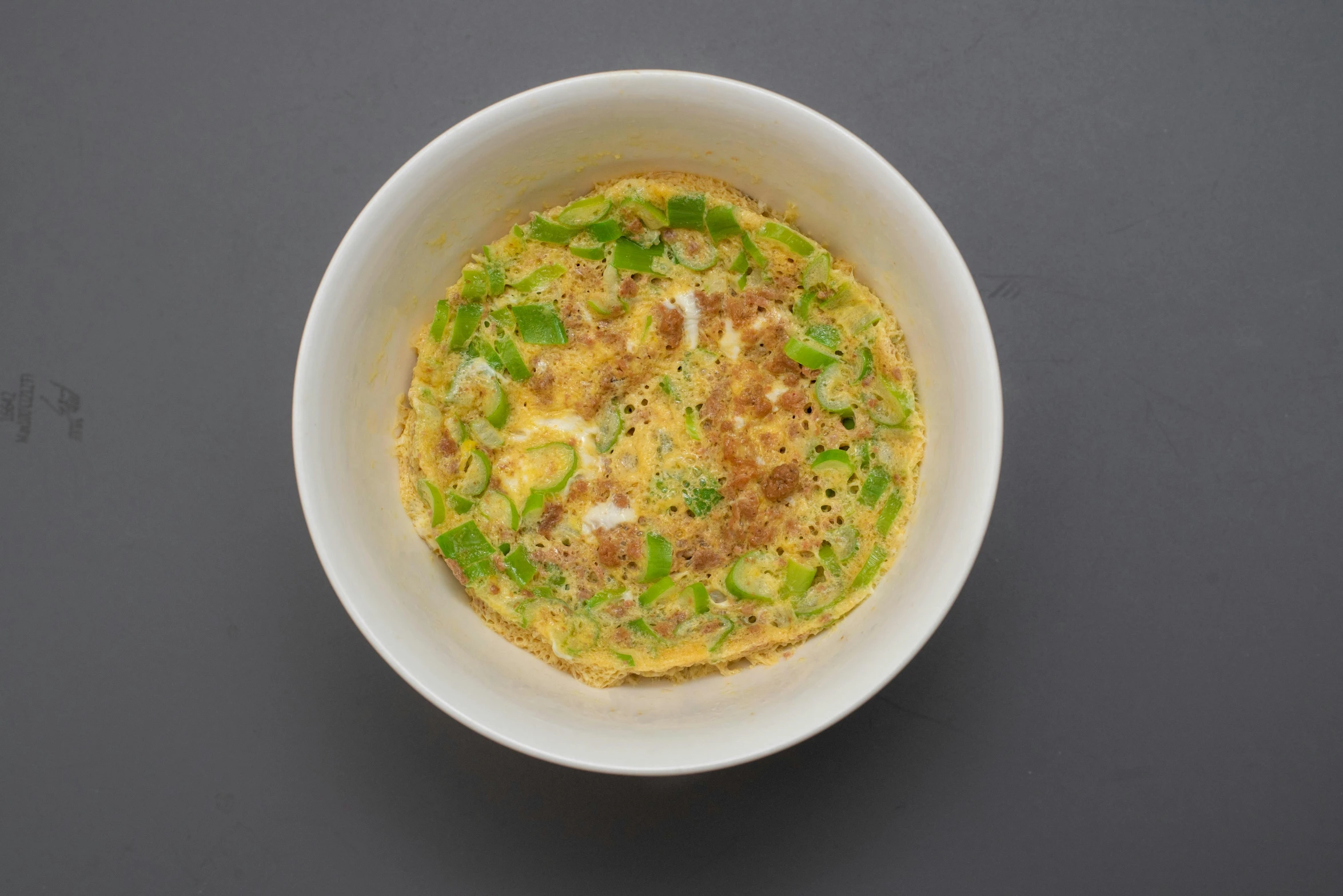 a white bowl filled with food sitting on top of a table