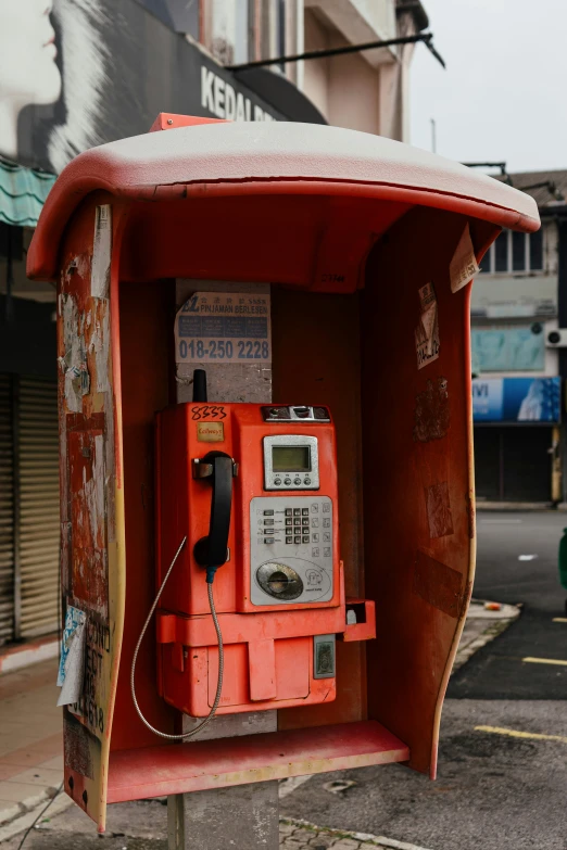 a pay phone stands on the street corner in front of a building