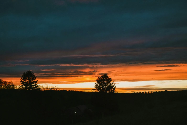 sunset in the distance with silhouettes of trees and mountains