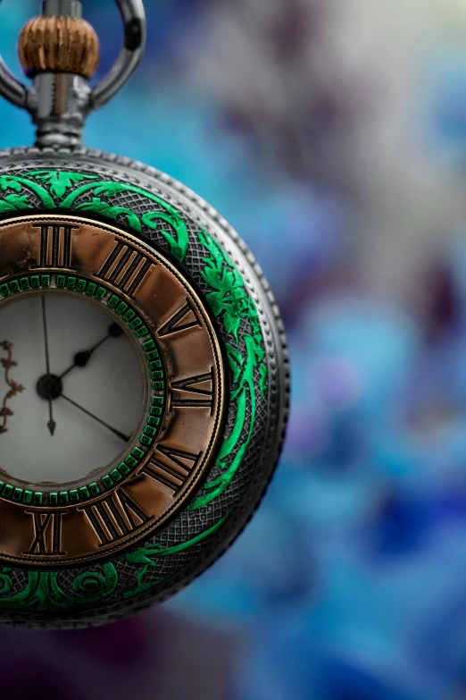 a pocket watch with a green decorated face is shown