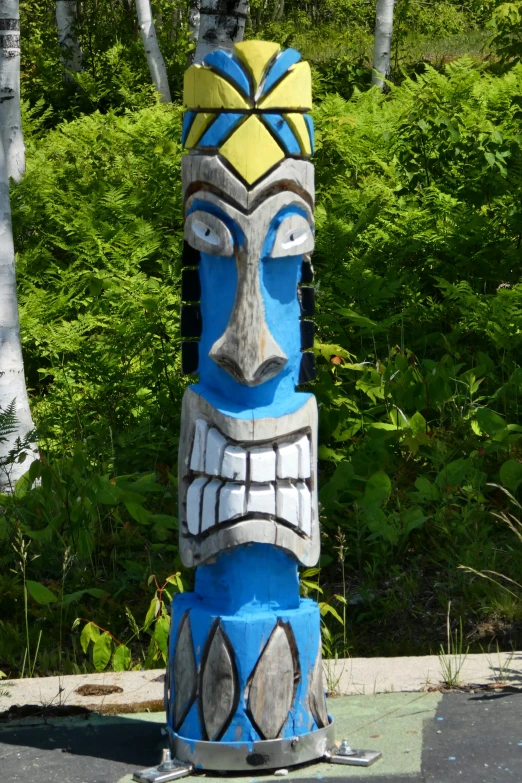 a colorful native totem sitting in front of green bushes