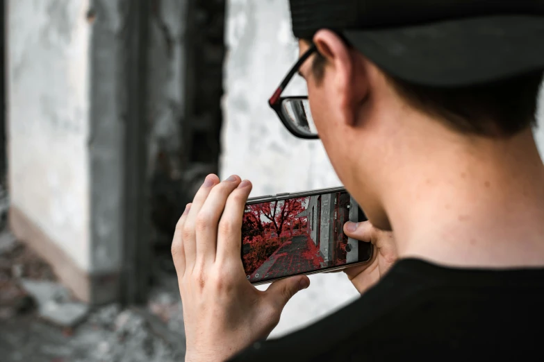 a man in black cap taking a po with his cell phone