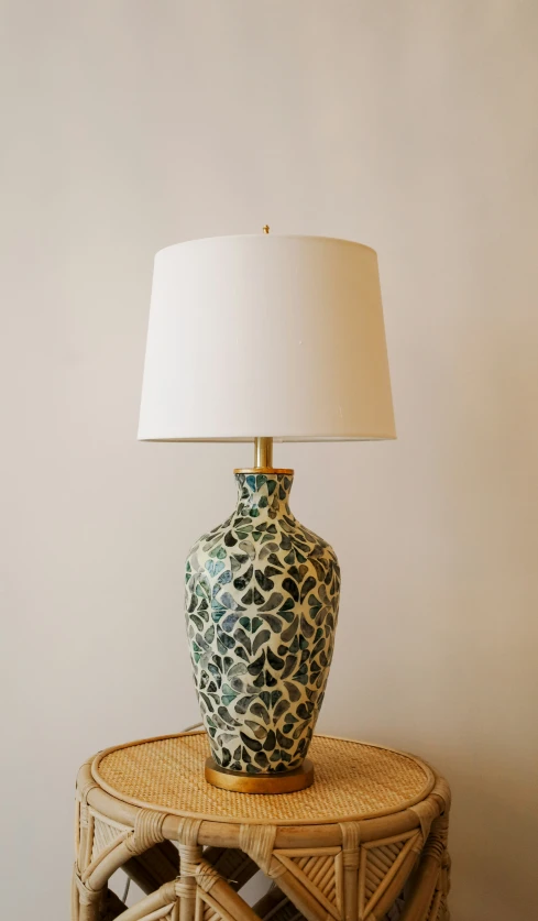 a table with a lamp, rattan basket and wicker shelf on top