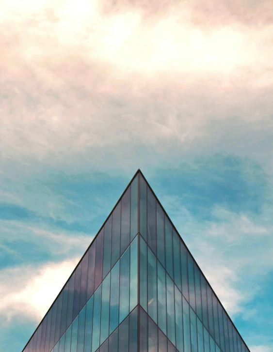 a very tall glass building against a cloudy sky