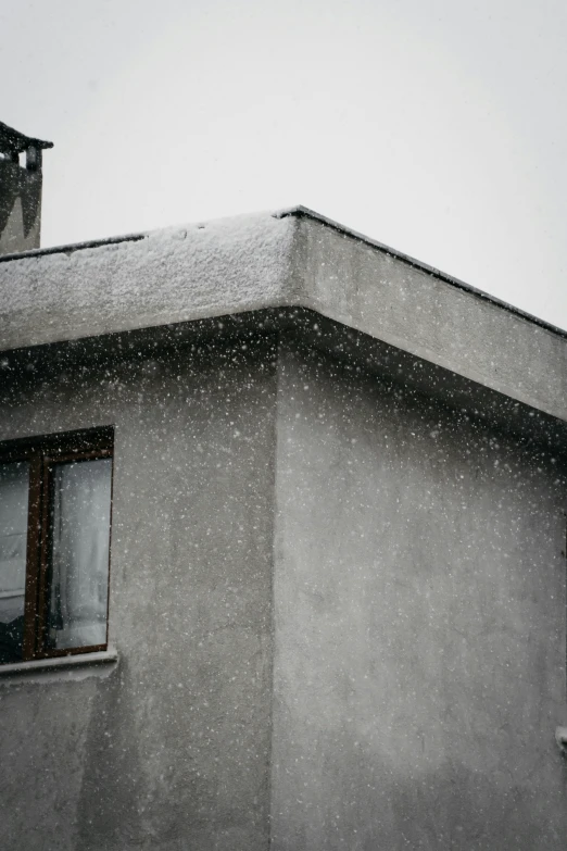 the roof of a building has snow falling