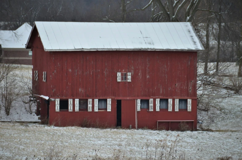 a barn in a snowy field that appears to be red
