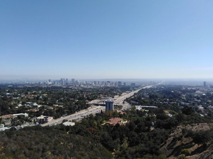 the view from atop a hill looking down on a highway and the city