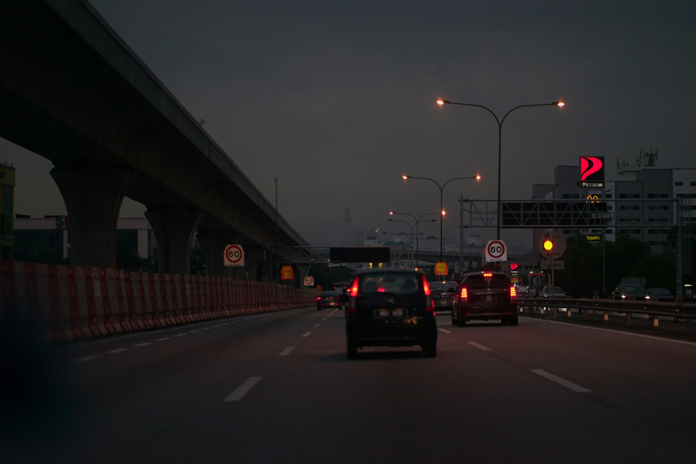 cars on road with traffic signs above at night